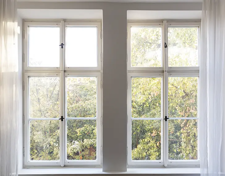 Tilbud på nye vinduer og hvordan jeg valgte leverandør. Billede af vinduer med buske i baggrunden.